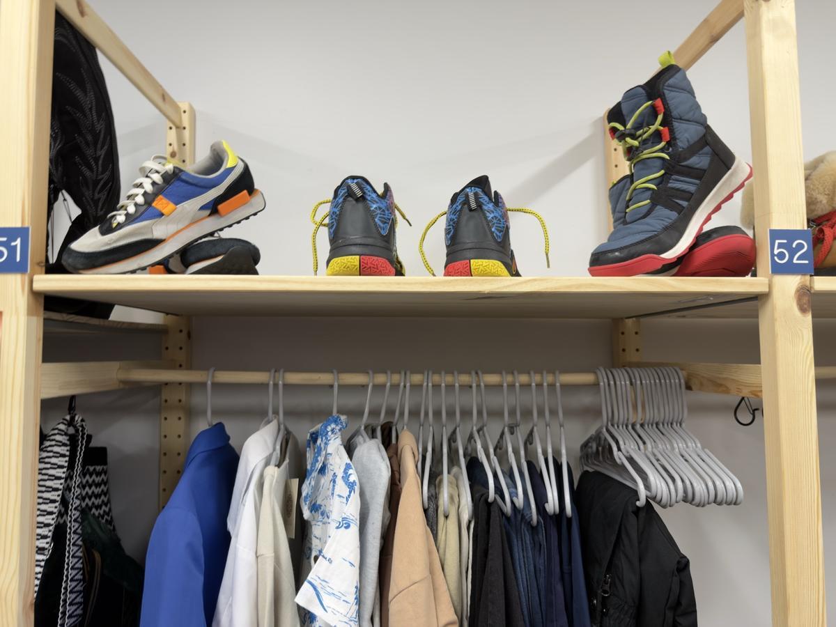 Shelf of gently used shoes above organized hangers and kids gear